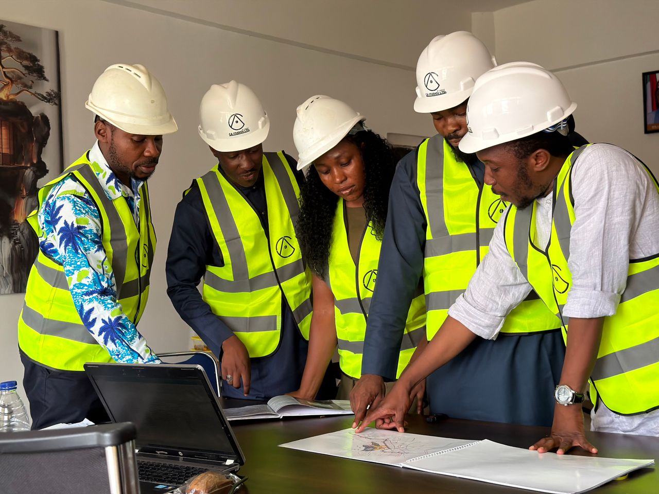services-01 Group of engineers in safety gear reviewing blueprints indoors.